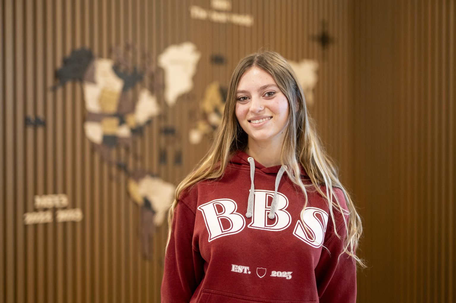 Uno studente BBS davanti alla mappa del mondo in legno