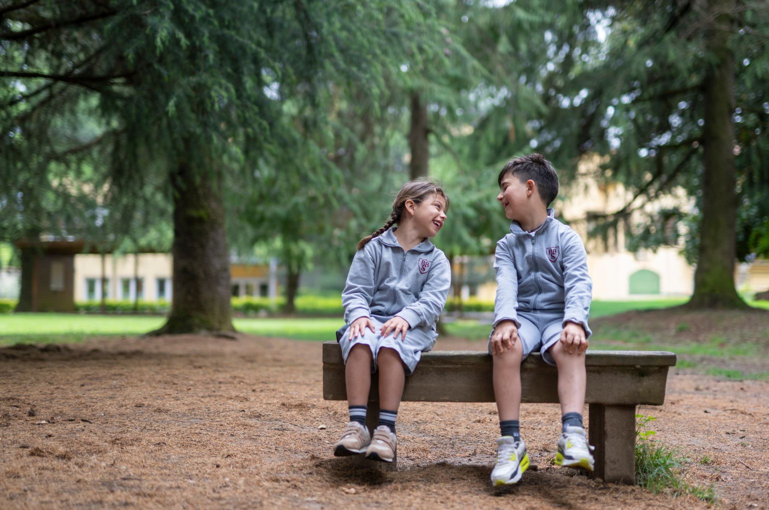 Due bambini BBS su una panca sotto gli alberi secolari