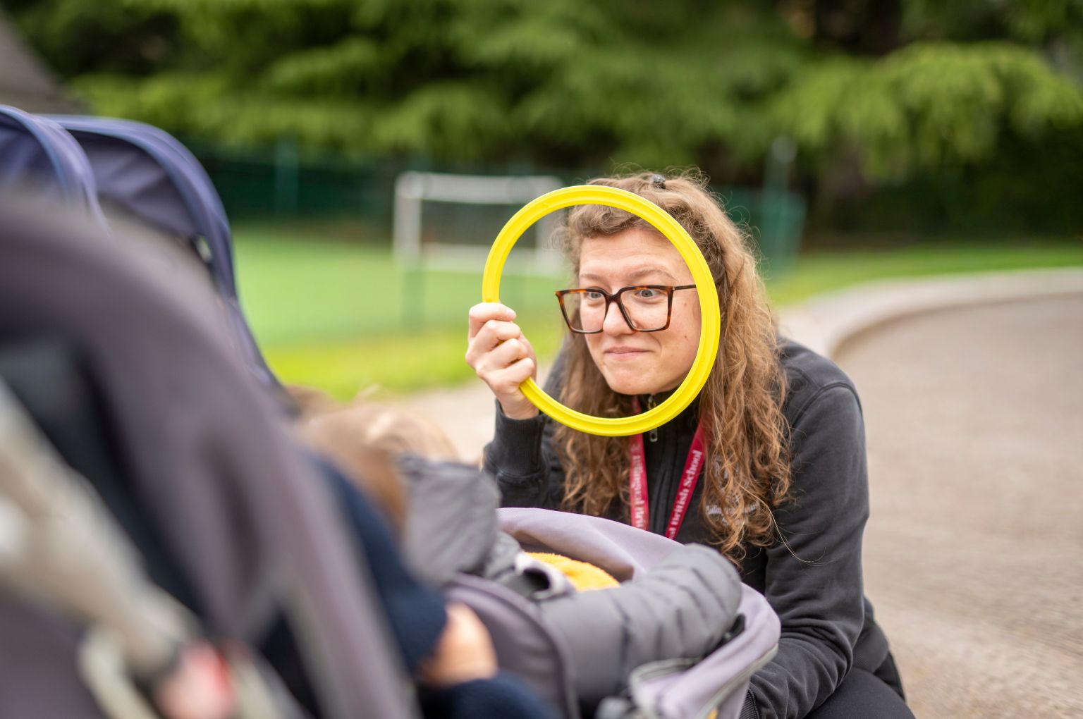 Un’educatrice che gioca a cucù con un bebè nel giardino della Nursery