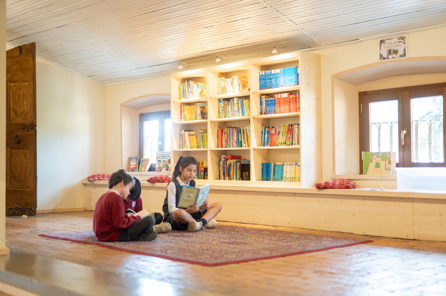 Bambini che leggono tra gli scaffali della biblioteca della Primary BBS