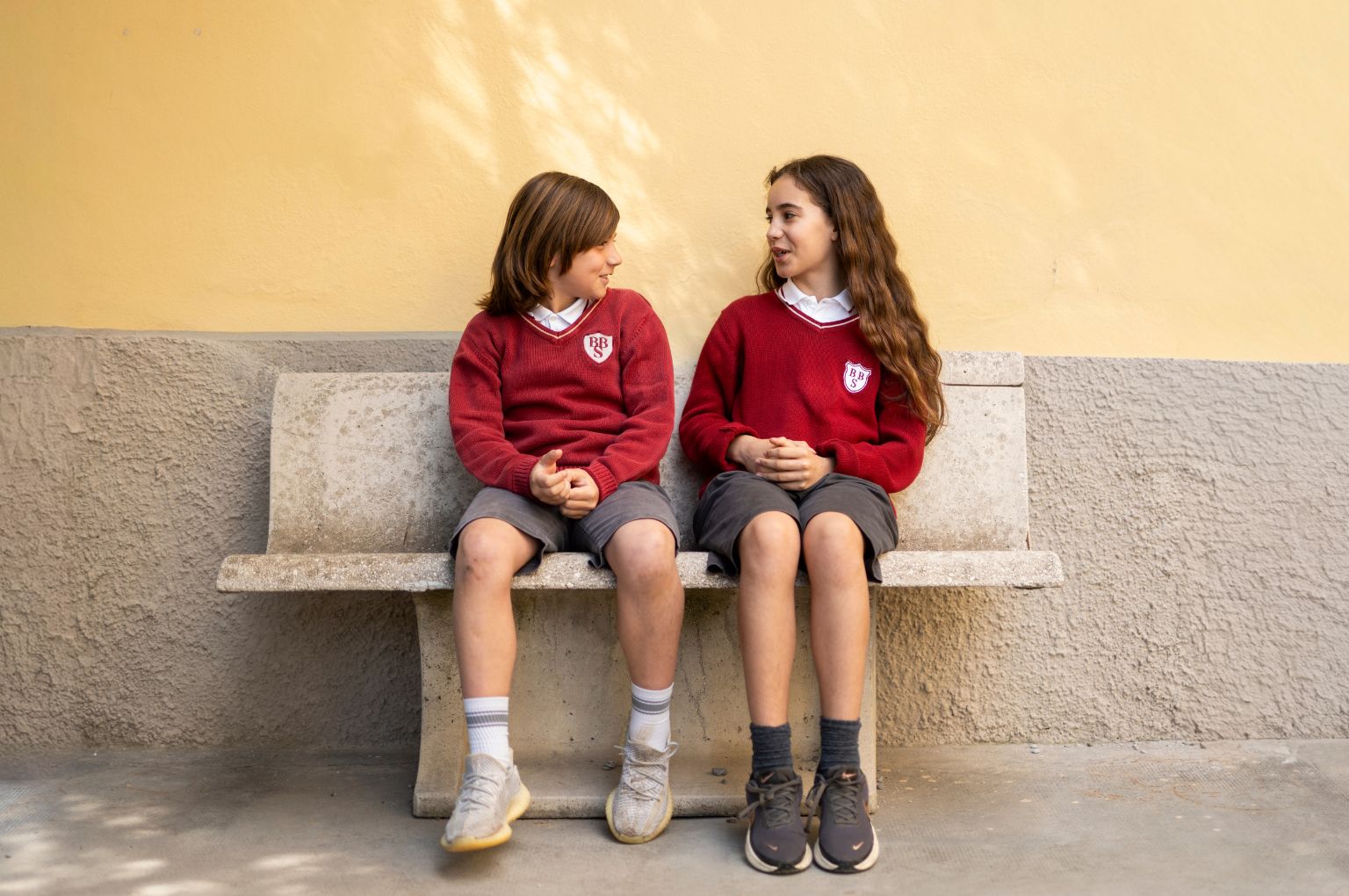 Due bambini BBS seduti su una panca di pietra nel campus storico
