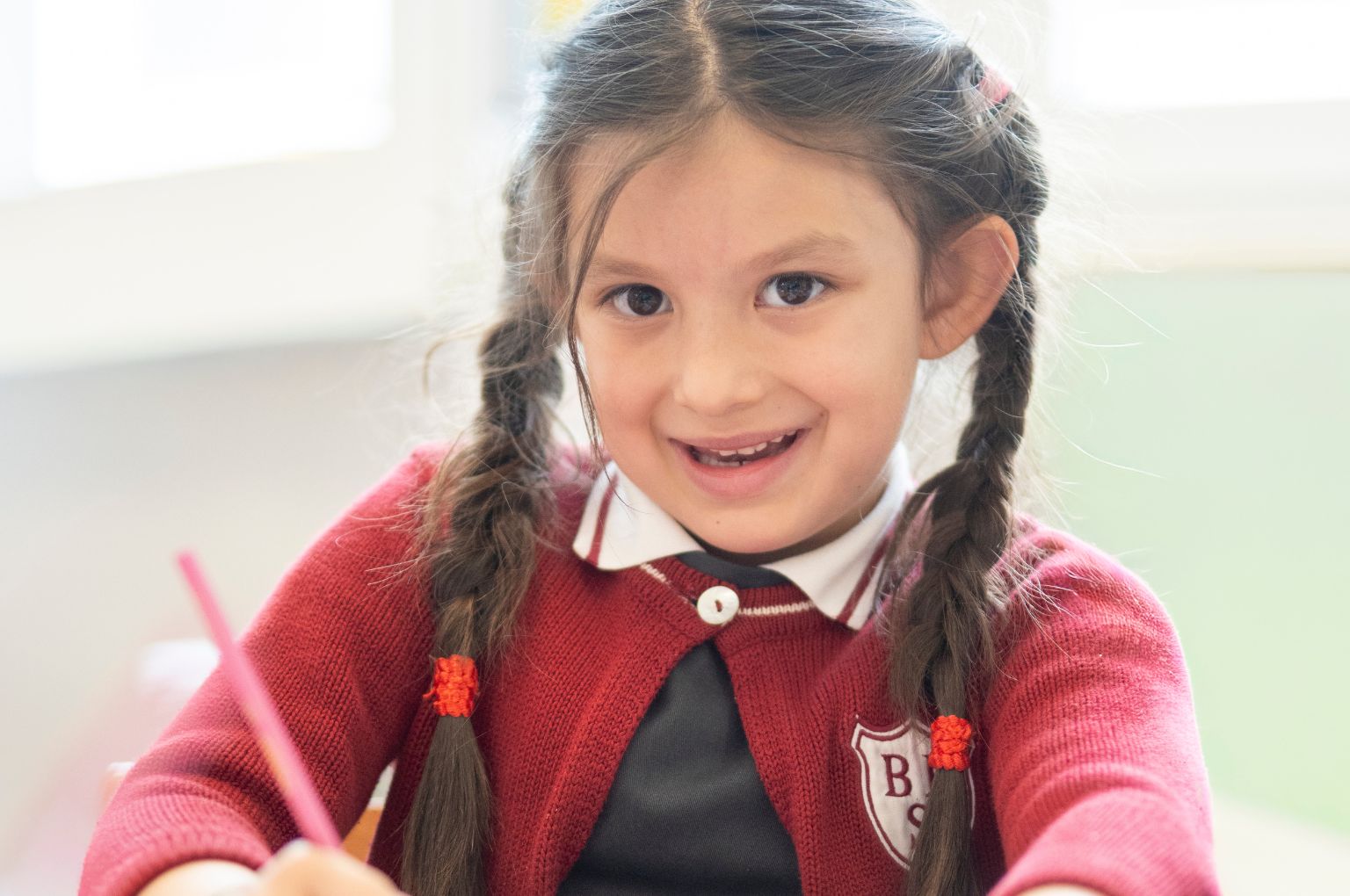 Un’alunna sorridente della BBS Primary al suo banco