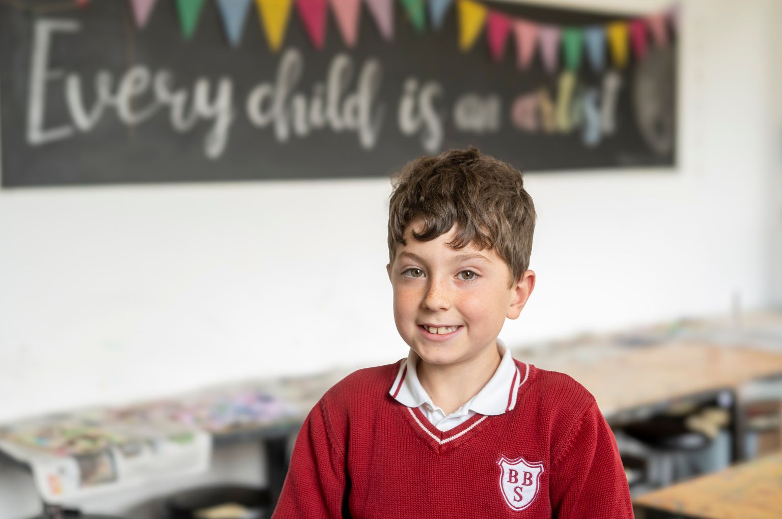 Un alunno BBS davanti alla lavagna con la scritta “every child is an artist”